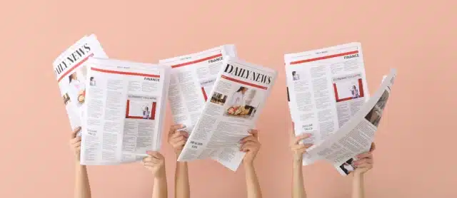 Hands holding newspapers in the air